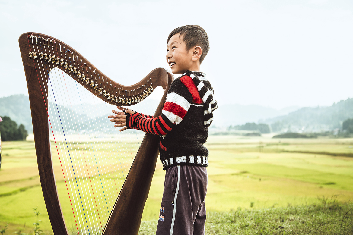 A young boy plays a harp at the Ziro Festival of Music, Arunachal Pradesh