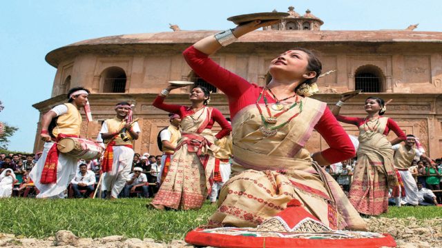 Dancers perform the Bihu dance against the backdrop of the Rang Ghar in Sivasagar, Assam
