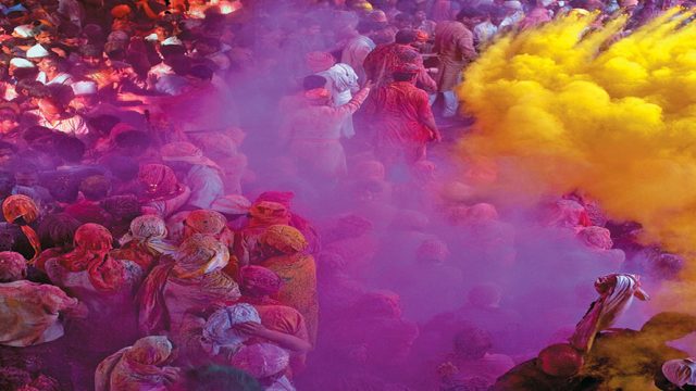 Revellers throw coloured powder in the air at the Radha Rani Temple in Barsana