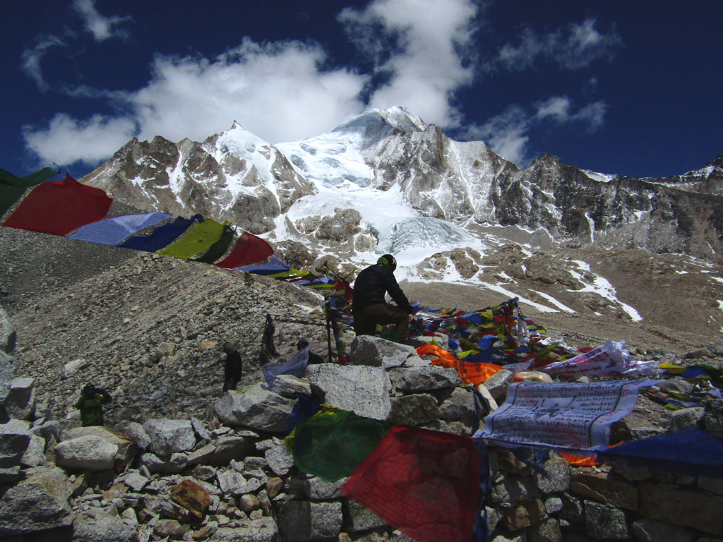 A trekker ties a Buddhist prayer flag at the Larkye La. The 5,160m pass divides the Budhi Gandaki valley and the Dudh Khola valley of the Annapurna region. In the background are the high ridges of the Cheo Himal