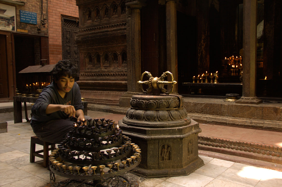 The Sakya god guardian of Mahabaudha lights lamps before the evening arati