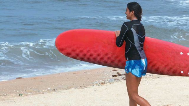 A surfer heads towards the sea with her board in hand