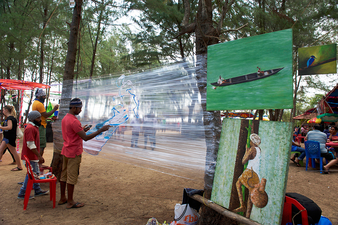 A group of artists draw a surfing scene on an interesting canvas