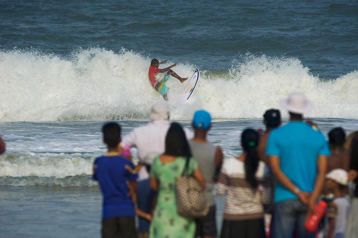 The crowd stares affixed at a surfer performing maneouvers