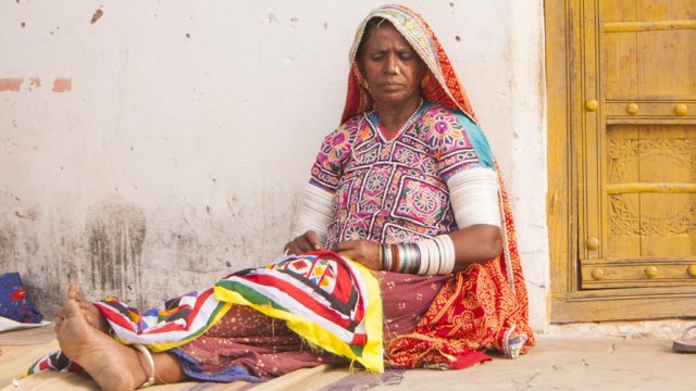 A traditional woman working on an ethnic embroidered cloth