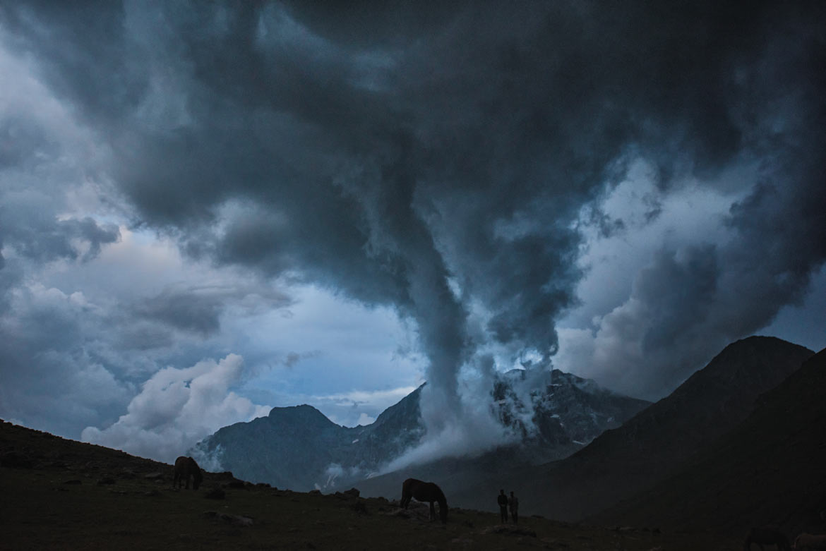 Their sheep safely corralled, a couple of Bakarwals watch a storm bear down on the valley