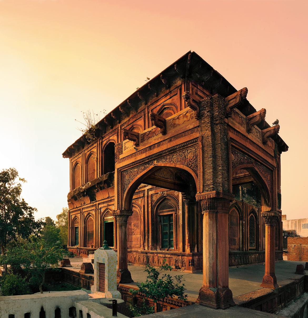 SHAH PIR TOMB, MEERUT: Between the Yamuna and Ganga, some 55 kilometres northeast of Delhi, is Meerut, a city with its own mint that rose to prominence under Akbar. The principal Mughal monument here is the mausoleum of a local saintly figure, known simply as Shah Pir, supposedly a spiritual teacher of Jahangir. Though the patronage of the tomb is credited to Nur Jahan, the building was never completed, leaving the saint’s grave exposed to the sky. The domeless, red sandstone structure is meticulously constructed, with well-articulated arched recesses on both its exterior and interior walls. The recesses are filled with diverse, jaali-like geometric patterns in intricately worked shallow relief, realised as perforated windows at both levels in the middle of each side. The tomb is raised on a terrace, and was intended to be surrounded by a colonnade, but only a corner portion of this was finished